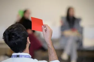 Image of a person holding up an orange post it note